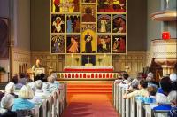 Interior of a church, pews filled with people listening to a lecture